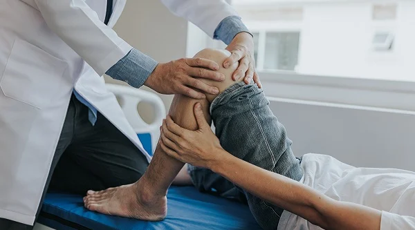 Especialista en ortopedia examinando la rodilla de un paciente
